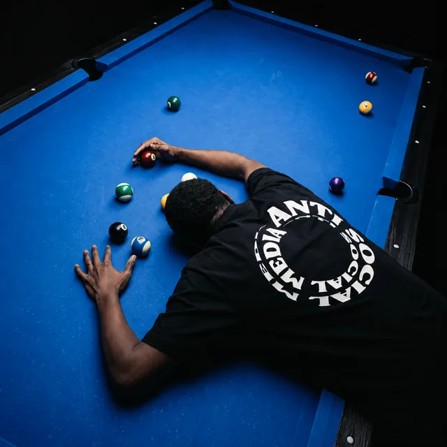 Someone leaning over a blue pool table in the ASMedia Circle tee