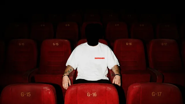 A bag-head in red cinema seats in the Chosen By Those tee
